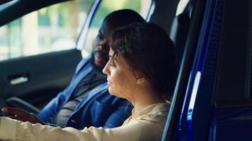 Man arguing with showroom salesperson after observing issues in vehicle during test drive. Upset woman at steering wheel next to husband telling agent concerns noticed after driving car, camera A photo