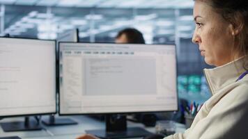 Smiling IT engineer in data center using PC to find misconfigurations affecting rackmounts. Cheerful woman checking servers bottlenecks leading to sluggish data transfer rates, camera B close up photo
