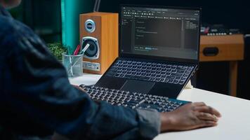 Teleworker in living room office using laptop to do coding for software developing, handheld camera shot. Remote employee typing on device keyboard, solving tasks in apartment, camera A close up photo