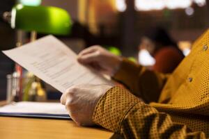 Public library scene with senior person studying under soft lighting, surrounded by books and paperwork, representing dedication to lifelong learning and the journey toward a university degree. photo