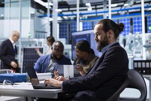 Factory scientists doing research and development, working on manufacturing automation advancements. Industrial plant experts analyze technical data during meeting, doing strategic production planning photo