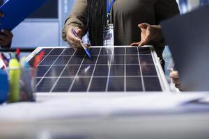 Photovoltaics factory expert reviewing solar panel design, discussing technical specifications and performance details during collaborative meeting focused on sustainable energy solutions, close up photo