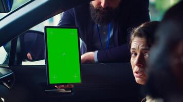 Salesman using green screen tablet to present car addons options to clients, after finishing test drive. Showroom agent mockup device to customers driving vehicle, camera A close up photo