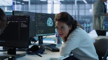 Happy technician chatting with colleague while doing maintenance on artificial intelligence neural networks. Jolly admin talking with coworker while using AI systems aiding processing, camera A photo