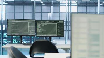 Computers in empty data center facility managing rackmounts energy consumption. Close up of script on PC monitors used for automation and monitoring processes in server room, handheld camera shot photo