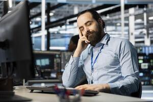 Exhausted server hub worker falling asleep at desk after repeated debugging attempts. Tired technician in data center sleeping in office after long hardware troubleshooting session photo