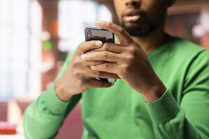 Man at home taking break from work to look at social media on mobile phone, having fun. Person in living room pausing tasks to use social network application on smartphone device, close up photo