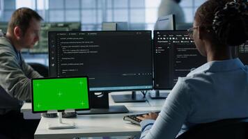 Isolated screen tablet in front of IT support workers coding on computers, upgrading equipment. Engineers at PC desk overseeing server clusters using chroma key device, camera A photo