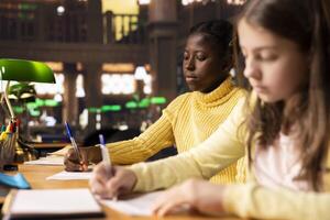Diverse teens studying at a library table with textbooks and pens, immersed in school assignments for the literature class lesson. Productive study time at a desk using academic materials. photo