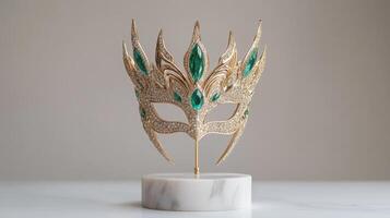 Ornate gold mask with emerald accents on a pedestal. photo