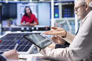 Factory experts design assembly facility production lines in tablet CAD program in videoconference. Employees use software on device to optimize factory production layouts in internet videocall photo
