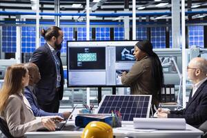 Factory management executives discuss solar panel technology and automation strategies, analyzing data to enhance sustainable manufacturing processes in advanced industrial facility photo