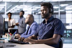 Cybersecurity expert wearing headphones, listening music while monitoring security incidents affecting server hub network. Developer hearing songs in data center and protecting company from threats photo