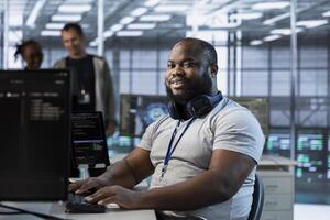 Portrait of smiling engineer in data center managing and optimizing IT infrastructure using network management skills. Happy man in server room upgrading equipment, reducing operational costs photo