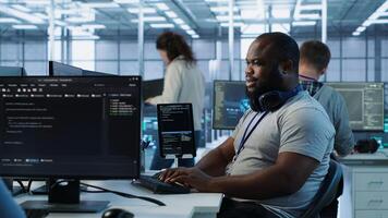 Happy computer scientist working in data center providing computing resources for different workloads. Cheerful IT specialist monitoring high tech supercomputers using tablet, camera A photo