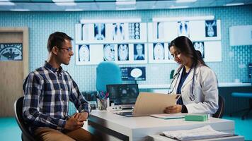 Physician meeting with patient to discuss medical test results in a cabinet, using advanced diagnostic tools to interpret x ray scans, demonstrating a professional healthcare approach. Camera B. photo