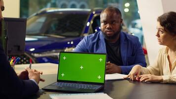 Dealership salesman looking over appointment list on chroma key laptop spreadsheet to schedule car test drive. Showroom agent arranging meeting with clients using isolated screen notebook, camera A photo