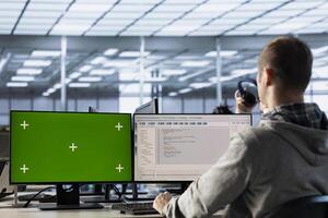 IT expert in server farm using green screen PC ensuring valuable data remains shielded from threats. Man safeguarding hardware against unauthorized access using mockup computer photo
