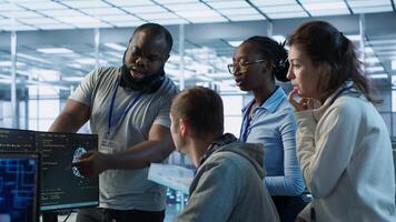 Technician doing brainstorming with colleagues to fix error in code affecting server room AI workloads. Team of artificial intelligence engineers repairing data center systems together, camera A photo