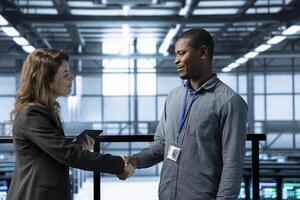 Data center system administrators meeting with inspector arriving in workplace to review equipment. IT specialist doing handshake with supervisor overseeing server farm infrastructure photo