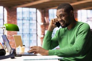 Happy man having friendly conversation with friends during telephone call using cellphone. Cheerful person at home having fun catching up with mates, talking on mobile phone photo