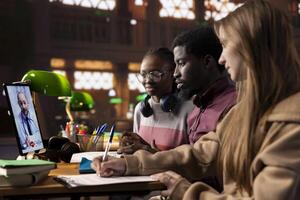 Diverse academic scholars in a library join a call with a medic tutor, enhancing their knowledge of science, treatment methods and telemedicine. Students learn about medical practice lessons. photo