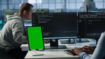 Green screen table in data center in front of IT support specialists working together, supervising server rows. Employees overseeing supercomputers using mockup device, camera A photo