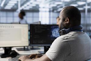 Computer scientist using artificial intelligence technology to optimize data center performance. African american IT expert in server farm using AI tech to accurately forecast potential issues photo