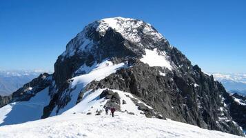 Majestic peak summit with climbers on snowy terrain. photo