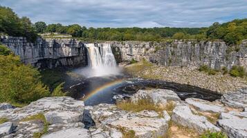 Majestic waterfall cascading over rocky cliffs, a vibrant rainbow arches above. photo