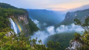 Misty valley landscape featuring a waterfall and rainbow. photo