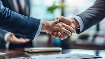 Two business people shaking hands over a desk photo