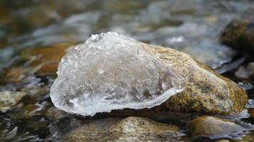 A small, frozen lump of ice rests on a rocky riverbed. photo