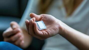 Close-up of a person holding a small, white adhesive patch. photo