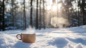 A warm cup of steaming coffee in a snowy forest. photo