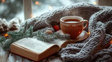 A cup of tea, a book and a christmas tree are on a window sill photo