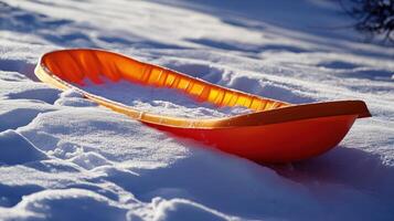 Orange plastic sled resting on snowy ground. photo