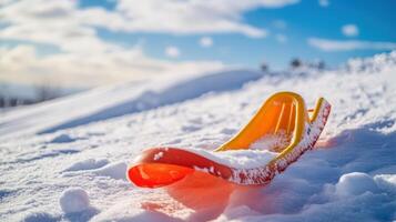 Brightly colored sled resting on a snowy hilltop. photo