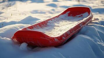 Red plastic sled resting on a snowy landscape. photo