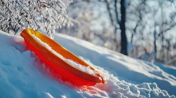 Orange sled resting on snowy hill slope in winter. photo