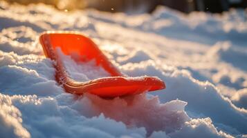 Orange sled nestled in a snowy landscape at sunset. photo