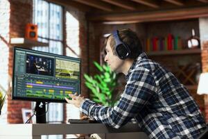 editor selecting key frames to use while doing montage, working from home on computer before deadline. Man using mouse to edit movie project footage in apartment office photo
