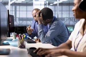 Technician doing face palm gesture, failing to optimize server farm for data processing requirements of customers. Upset man in data center struggling to make equipment operate efficiently photo