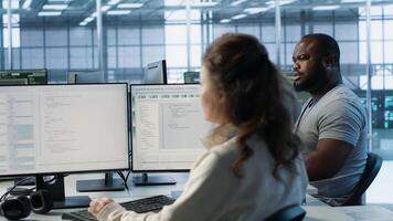 Employee sitting next to african american coworkers in data center doing checkup on electronics to avoid downtime. Engineer and colleagues supervising server room infrastructure components, camera A photo