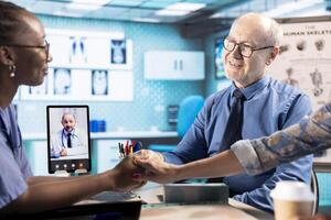 African american nurse doing comforting gesture for senior people on web call with specialist, holding hands with patients and encouraging them while they discuss with doctor remotely. Telemedicine. photo