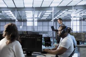 African american man in data center coordinating deployment of server architecture, improving data processing speed. Worker listening music in server farm, configuring and testing equipment photo