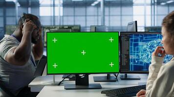 Employee working on green screen computer in server hub, using AI to process data. IT developer at chroma key PC updating servers controlling network resources using artificial intelligence, camera A photo