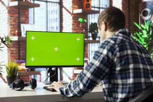 Freelancer in living room office using chroma key PC to answer emails from business associates. Remote worker typing on isolated screen device keyboard, solving tasks in apartment photo