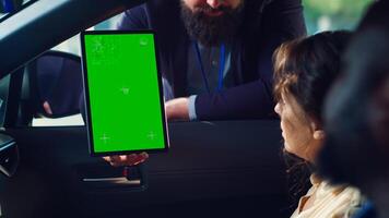 Car salesperson showing vehicle final price on isolated screen tablet to clients after finishing test drive. Dealership agent showing automobile catalog to customers on chroma key device, camera A photo
