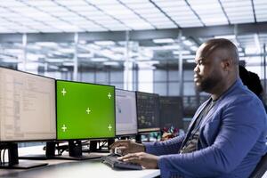 Engineer in server hub using green screen computer to find firewall misconfigurations affecting performance. Man checking systems bottlenecks leading to sluggish data transfer rates using mockup PC photo